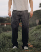 Person wearing dark pants and a light shirt standing in a grassy outdoor area.